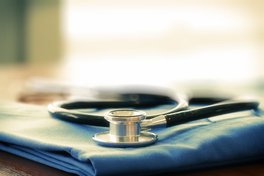Stethoscope with blue doctor coat on wooden table with shallow DOF evenly matched and background-1